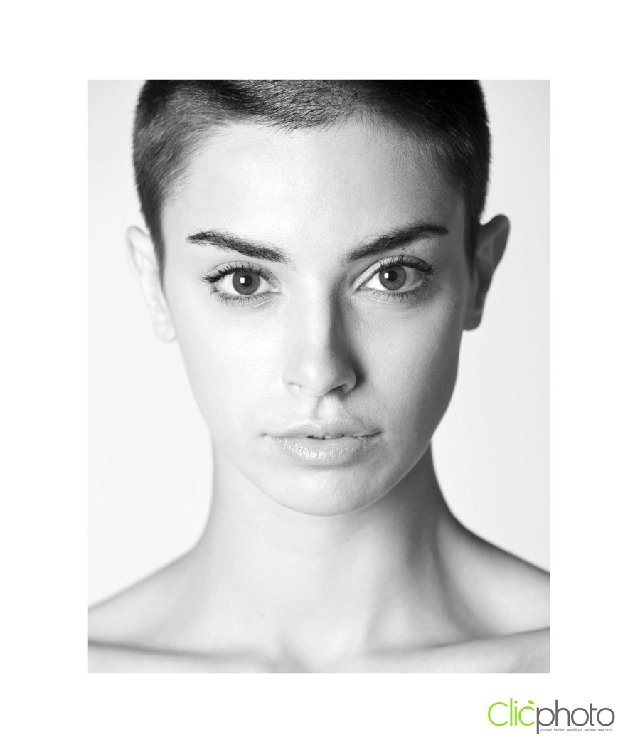 Female model photographed in black and white facing the camera. Hair buzzed close to her head. Clic Photo logo in bottom right corner