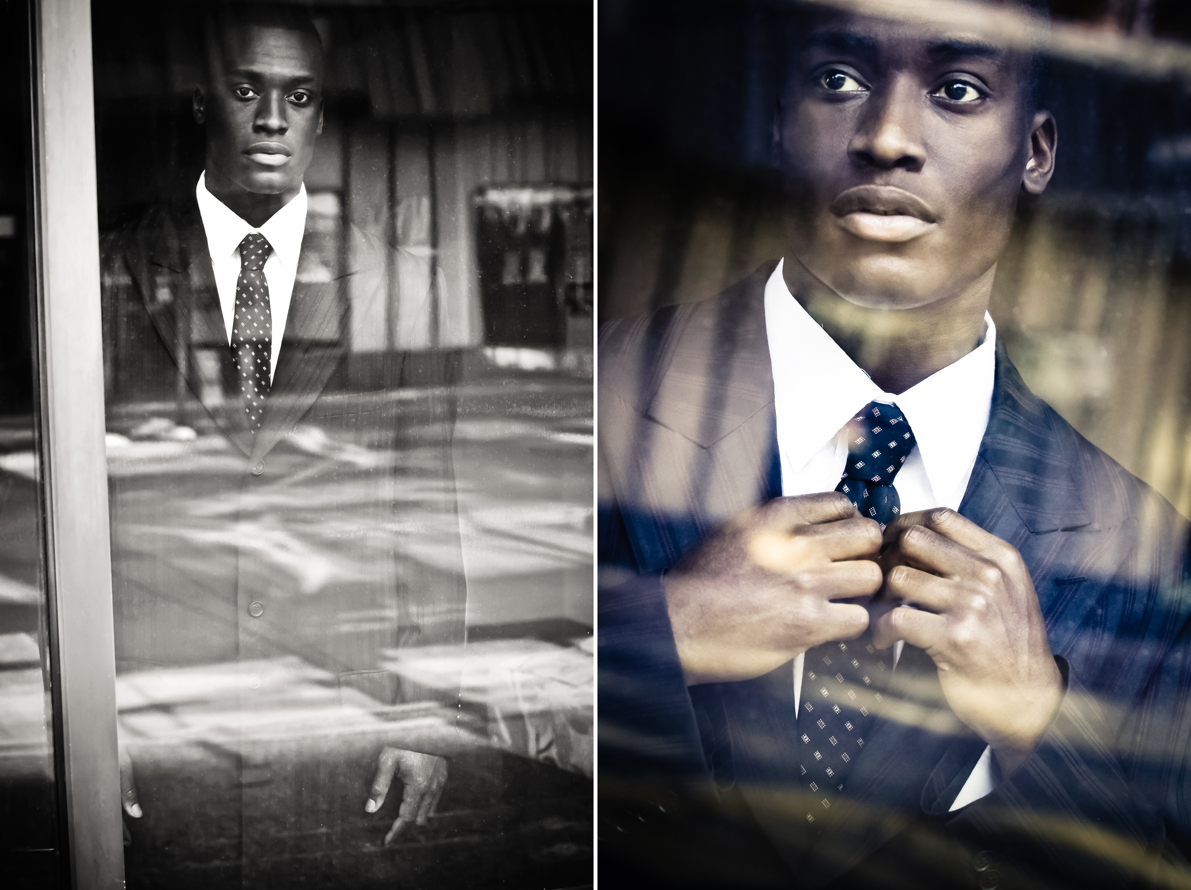 A male model stands behind a reflecting window facing the photographer while wearing a suit with pattered tie