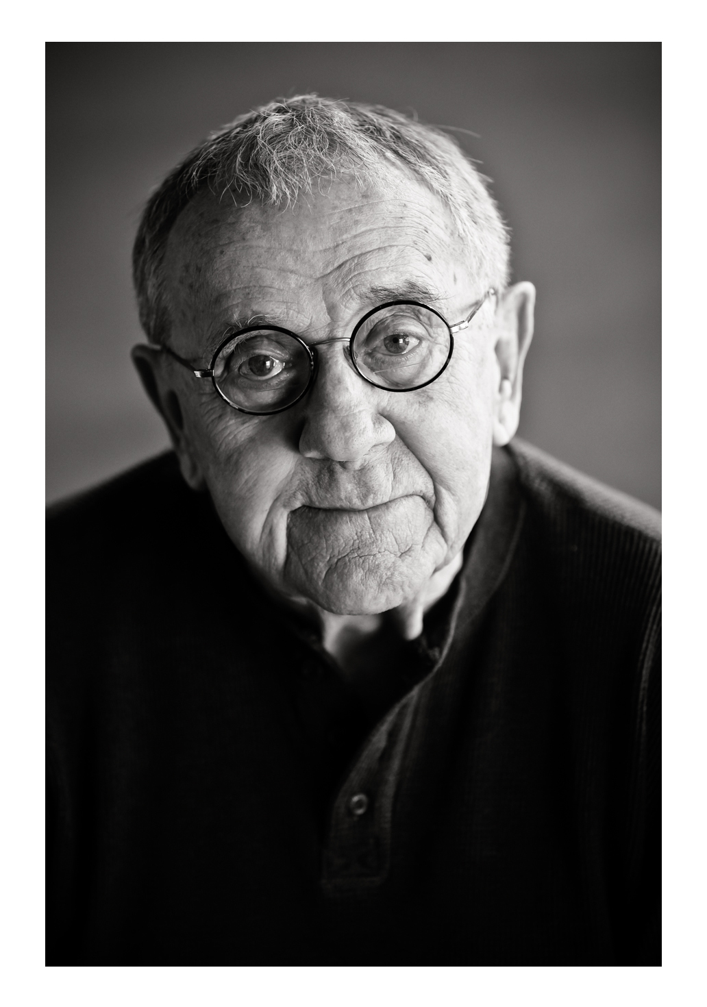 An elderly man wearing glasses faces the photographer with a warm smile while wearing a dark button-up shirt. Had a great time working on location