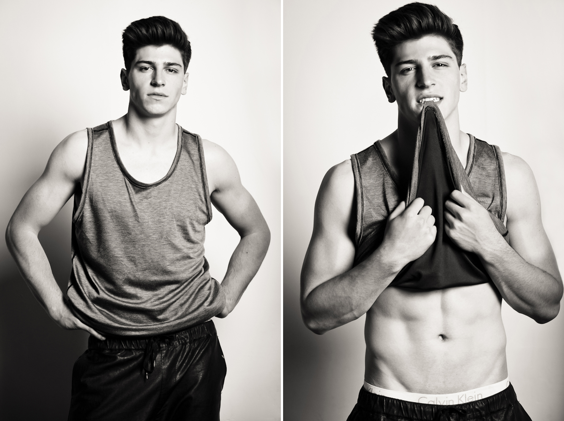 A young male model with dark, high-coiffed hair stands in a tank top and black sweatpants looking toward the photographer