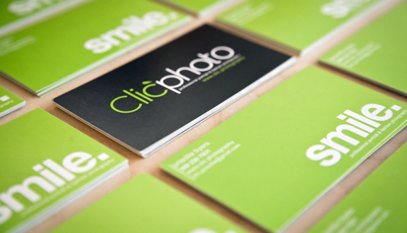 A field of green smile. business cards with a stack of back Clic Photo business cards in the background